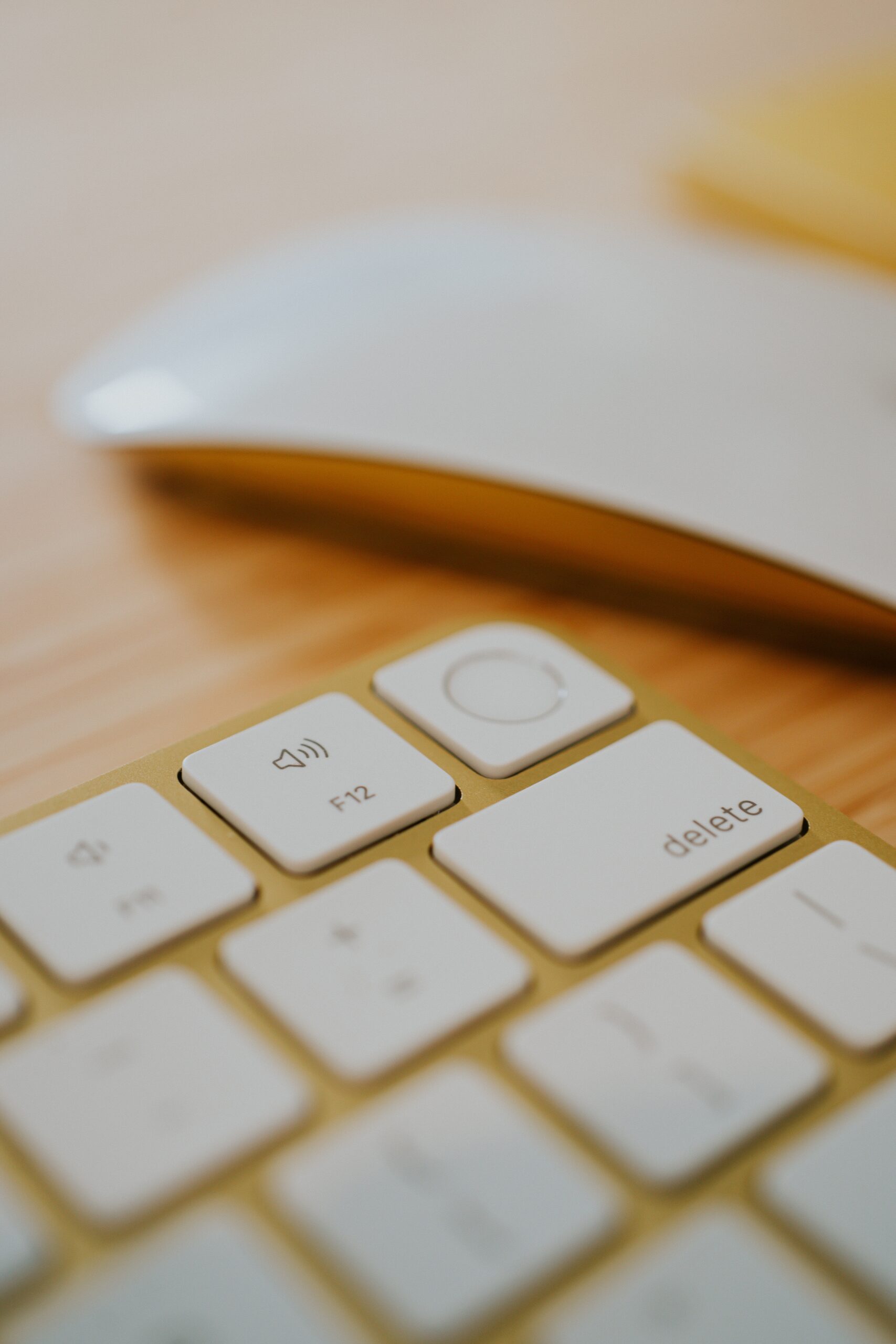 Yellow Apple keyboard with Touch ID fingerprint scanner with yellow Magic Mouse on a desk in a home office.